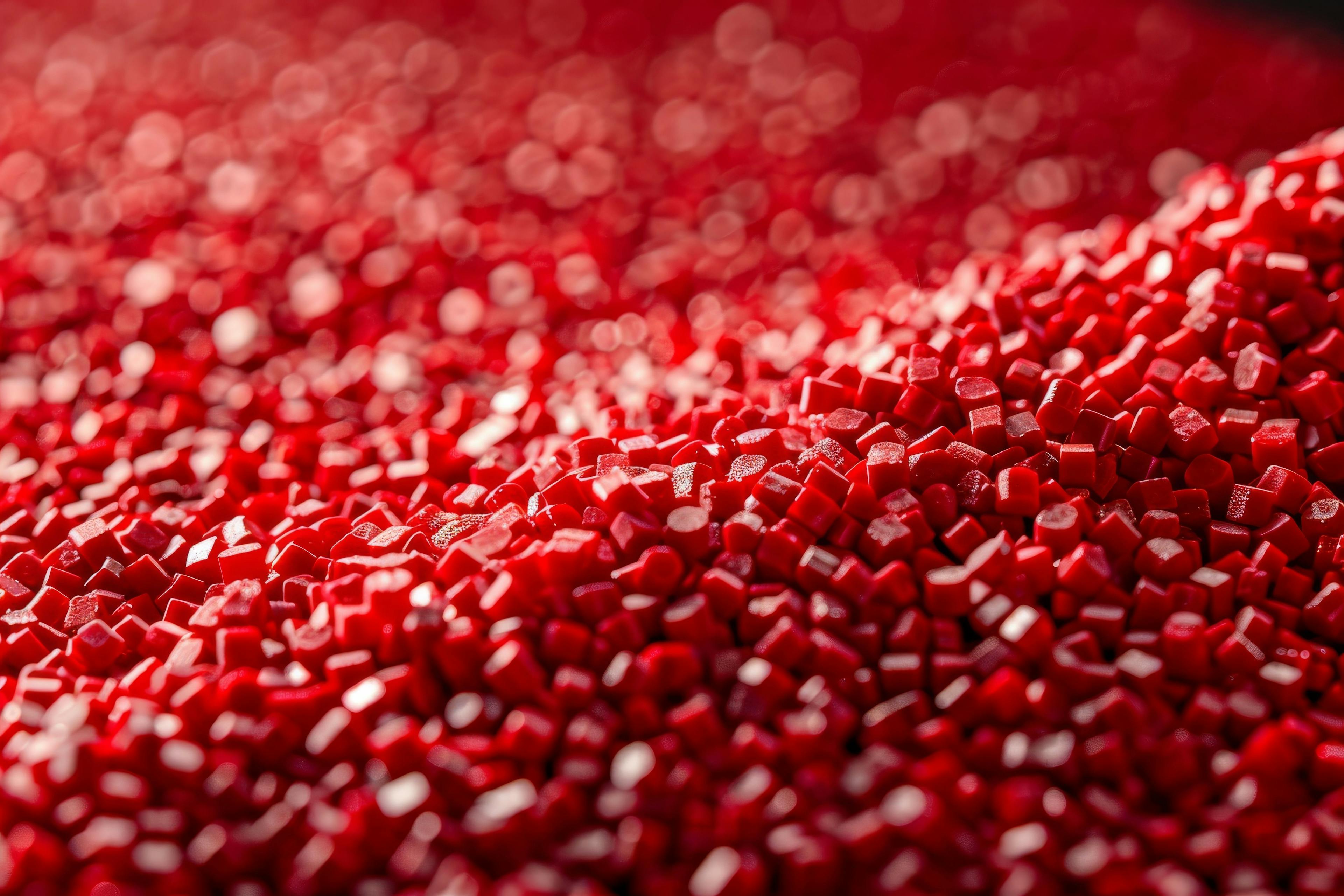 A macro image capturing the smooth, glossy surface of uniform red polymer granules (Generated with AI) | Image Credit: ©Elmira - stock.adobe.com