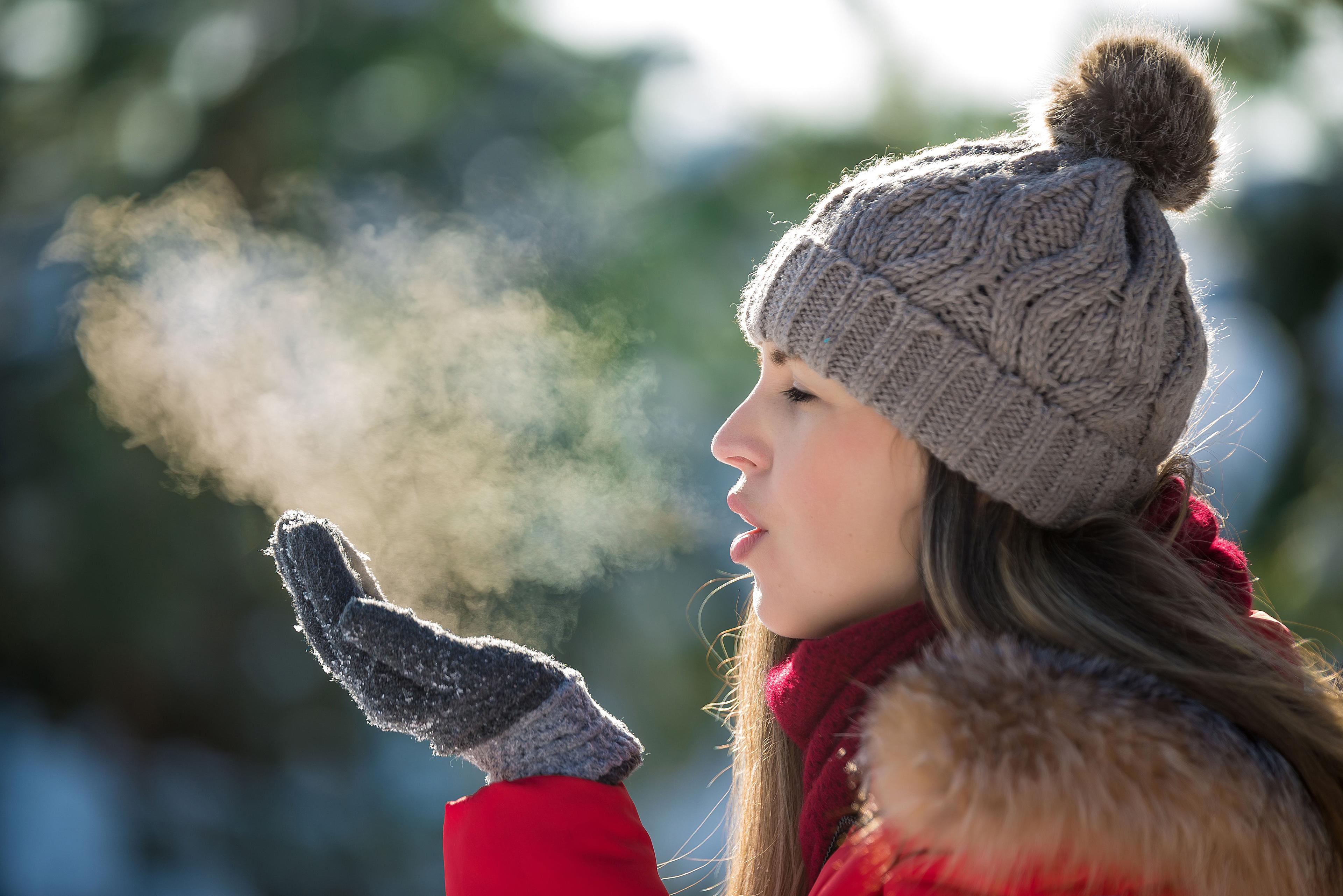 Young woman breathes out steam outdoor in winter. © illustrisima- stock.adobe.com