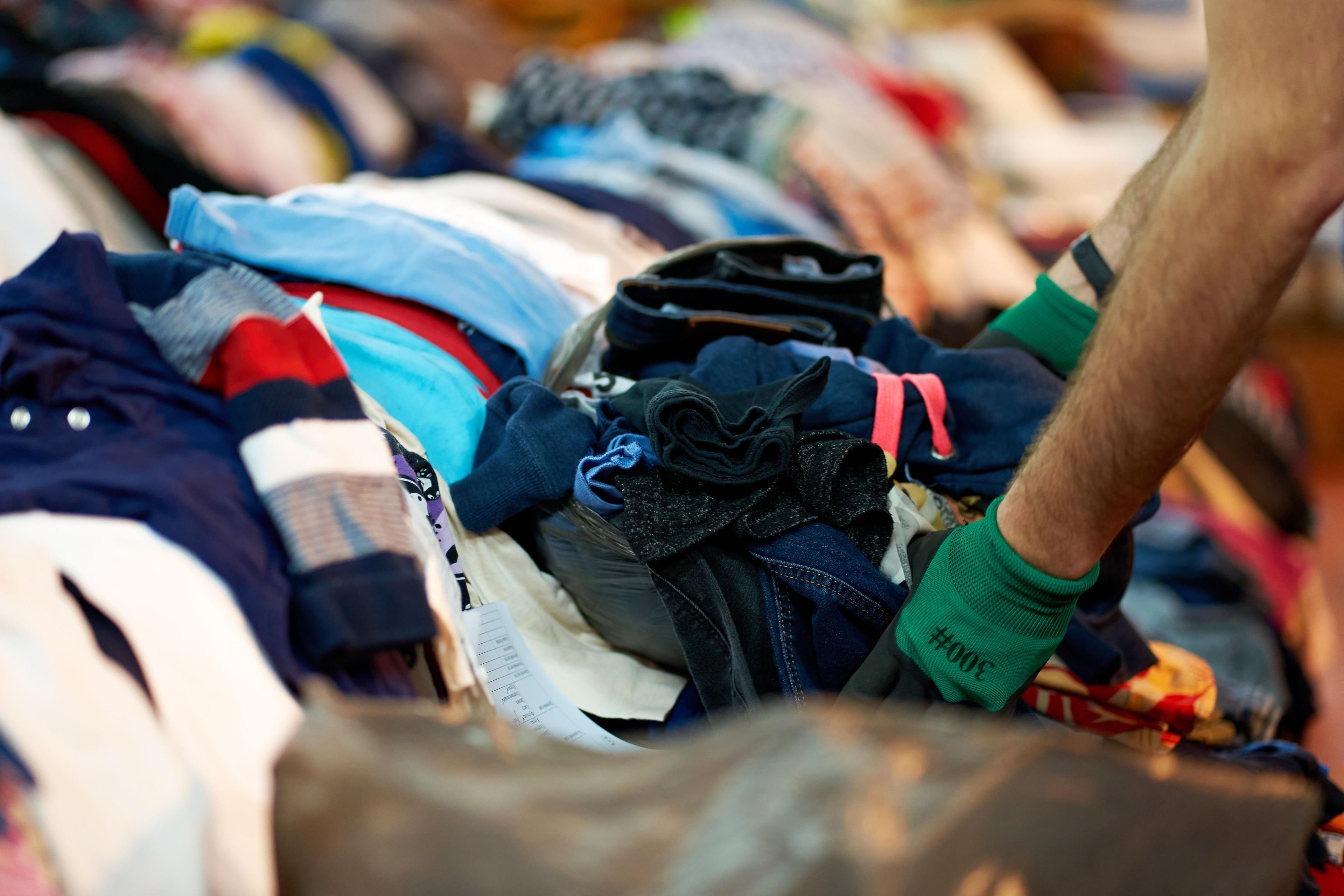 Person sorting second hand clothes by size and gender | Image Credit: © Kate - stock.adobe.com