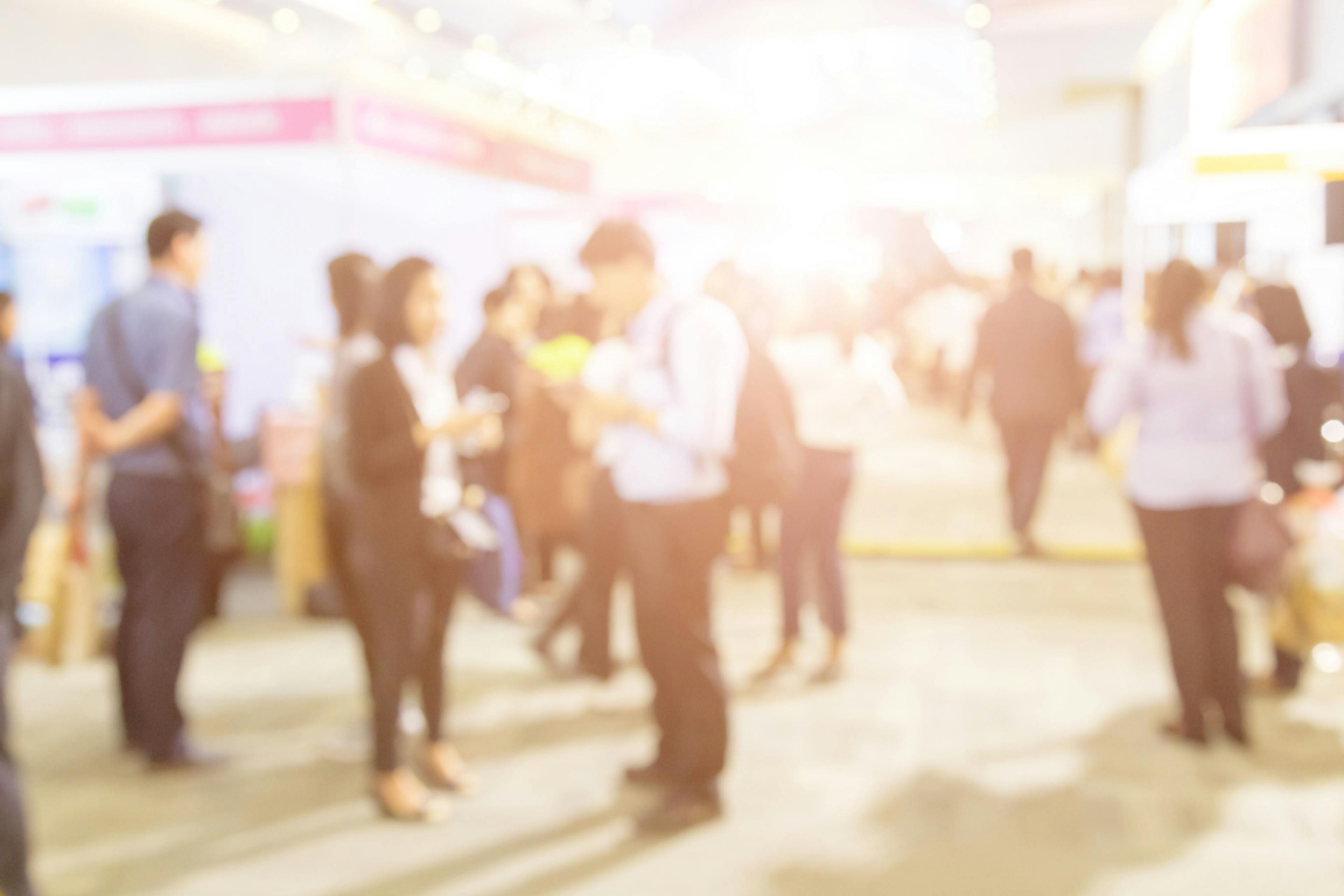 Blurred background of public exhibition hall. Business tradeshow, job fair, or stock market. Organization or company event, commercial trading, or shopping mall marketing advertisement concept | Image Credit: © PRASERT - stock.adobe.com