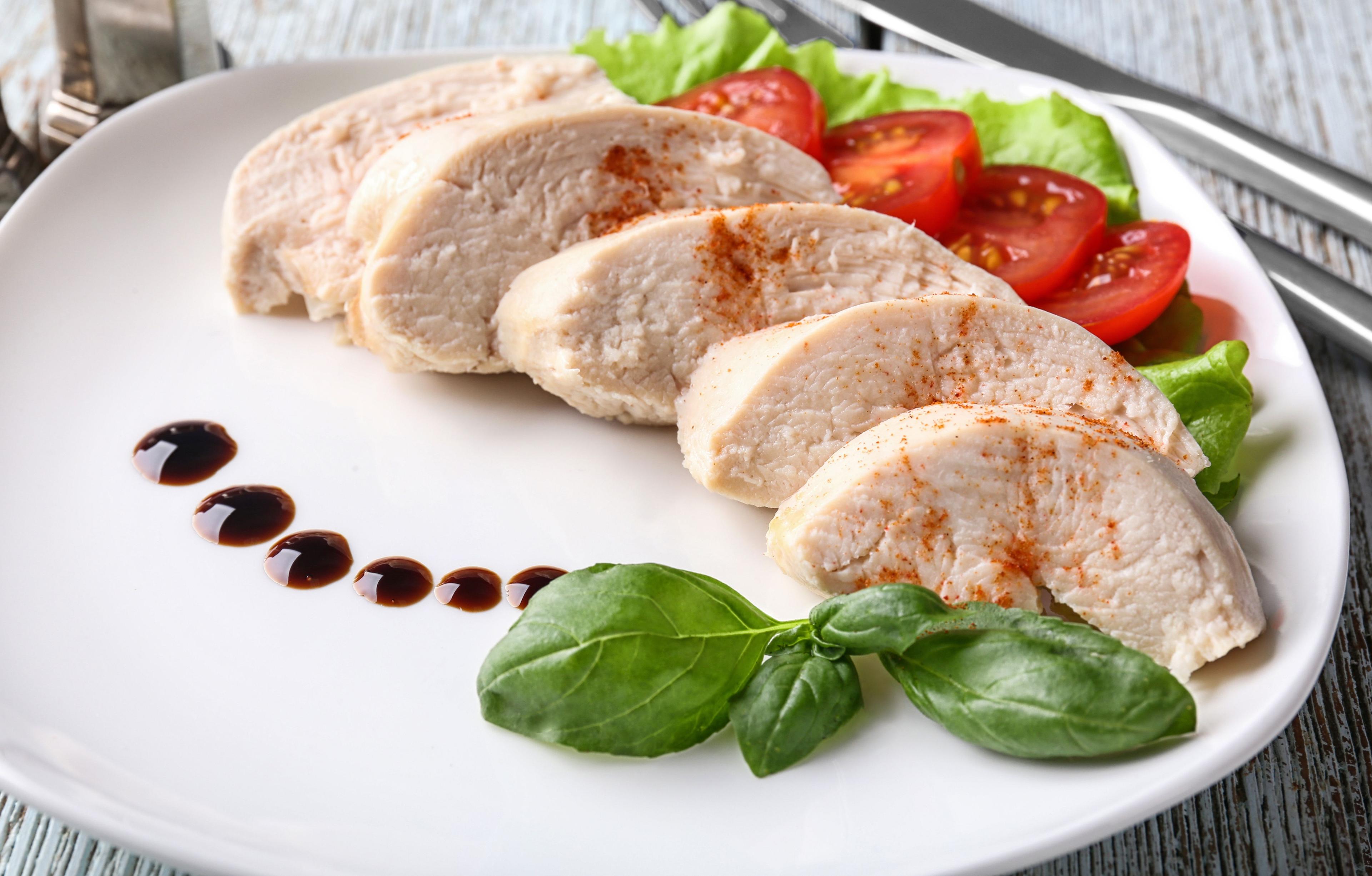 Plate with boiled chicken fillet and garnish on table. © Pixel-Shot - stock.adobe.com