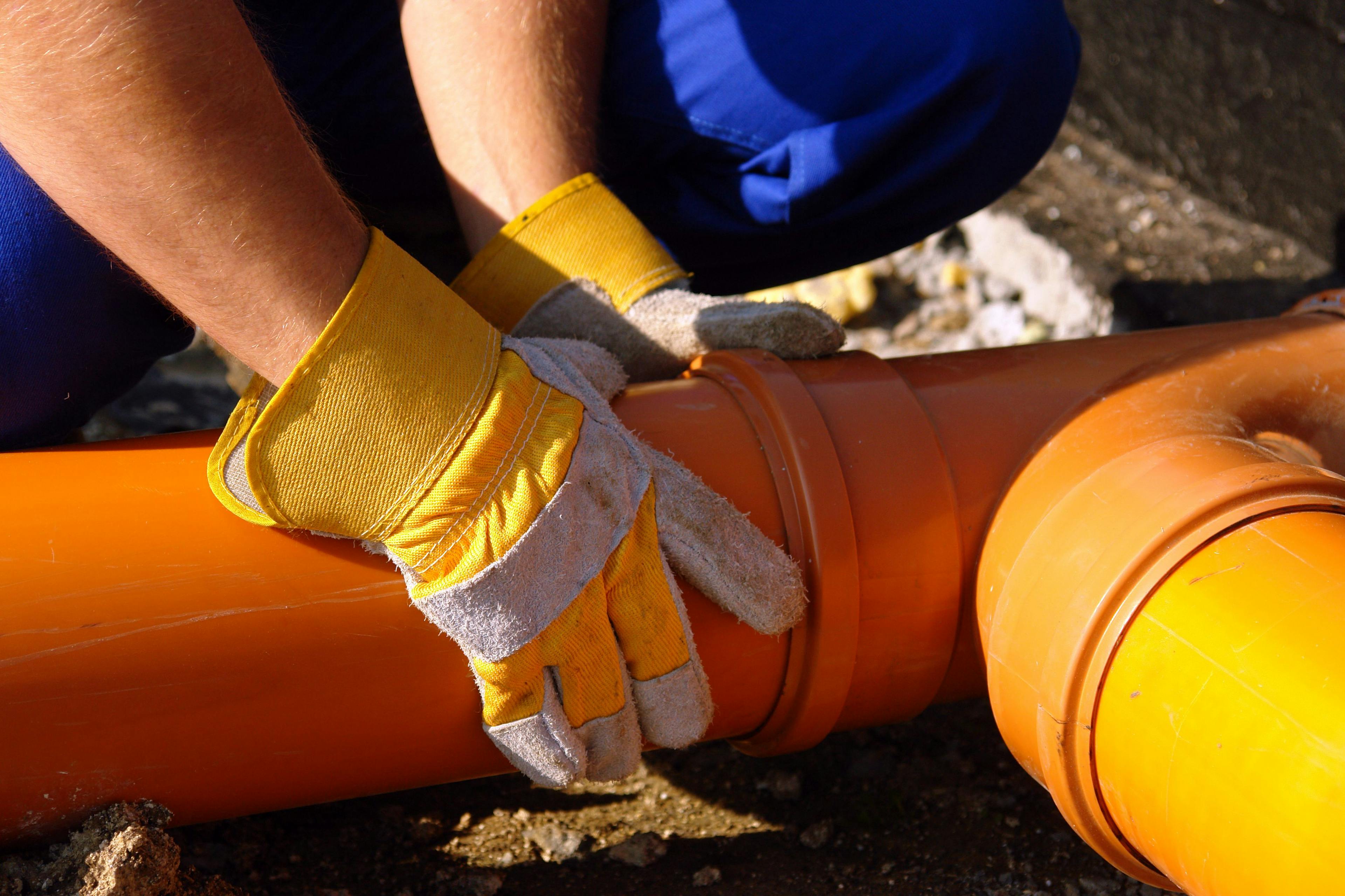 Closeup of plumber's hands assembling pvc sewage pipes | Image Credit: © Roman Milert - stock.adobe.com